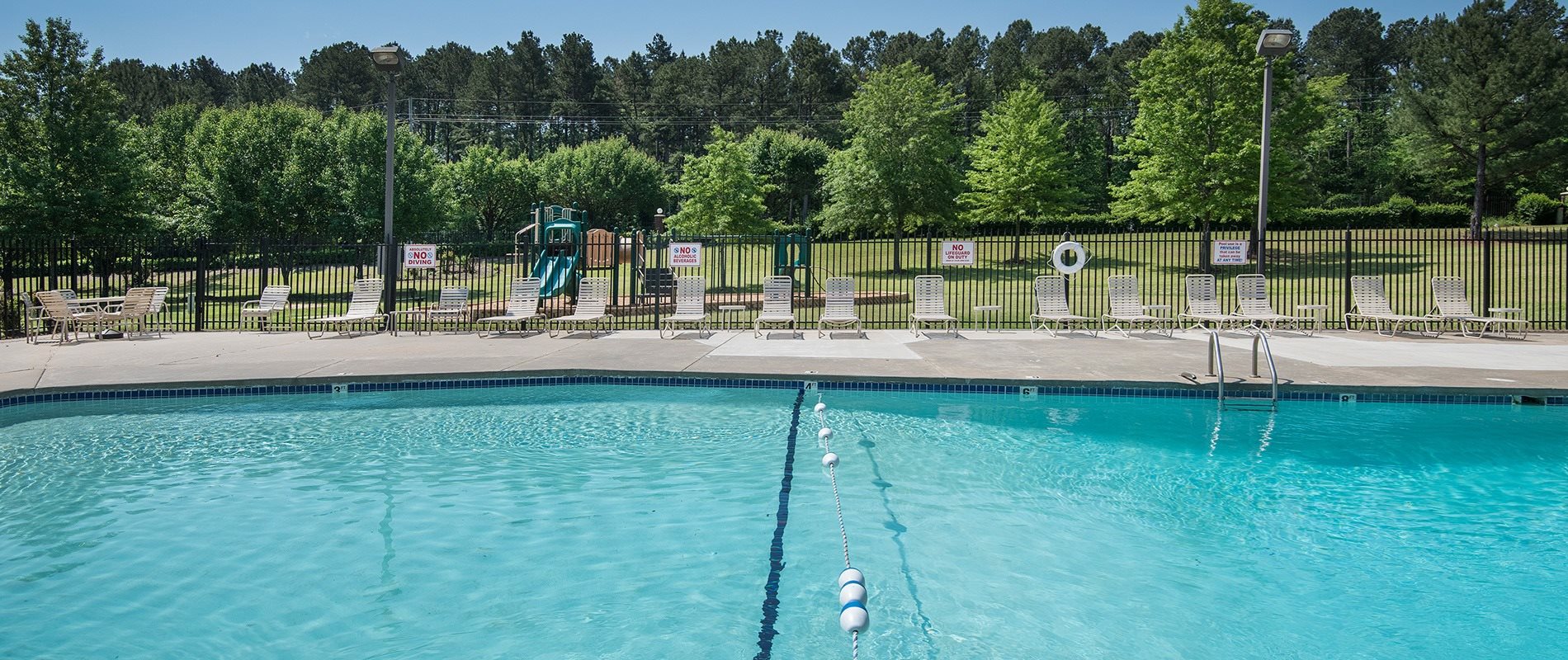 A swimming pool with a diving board and lounge chairs.